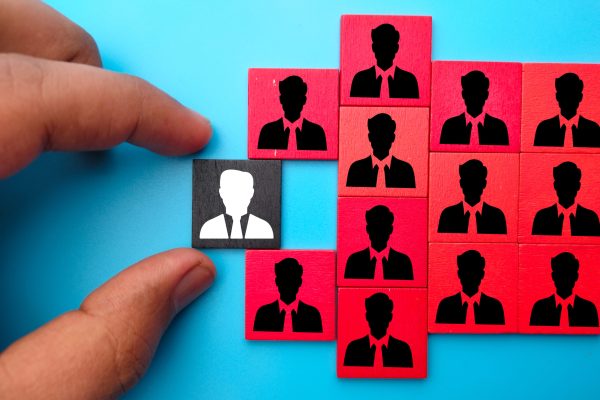 Close-up shot of a hand holding squares with an old employee and new employee icons A close-up shot of a hand holding squares with an old employee and new employee icons