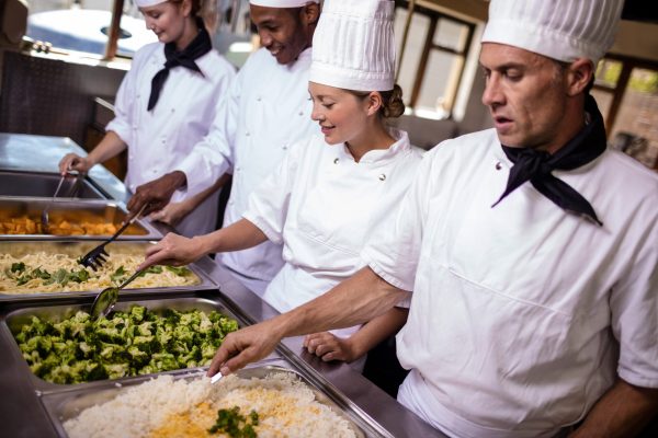 Group of chefs stirring prepard foods in kitchen at hotel Group of chefs stirring prepard foods in kitchen at hotel